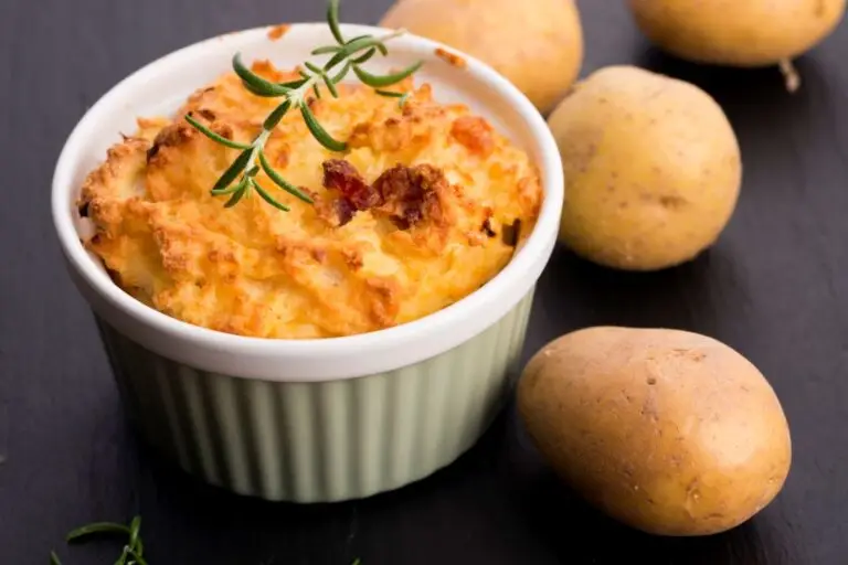 Whipped potato souffle in a white ramekin garnished with rosemary.