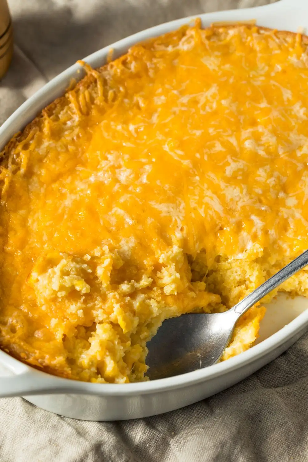 Corn pudding casserole topped with cheddar cheese