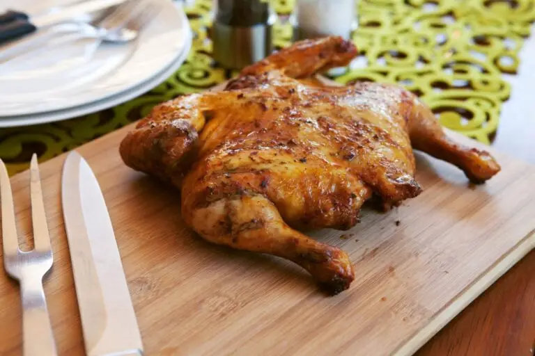 Split roasted chicken on wood plank