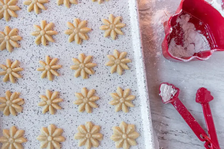 Raw dough Christmas spritz cookies pressed shapes on baking sheet