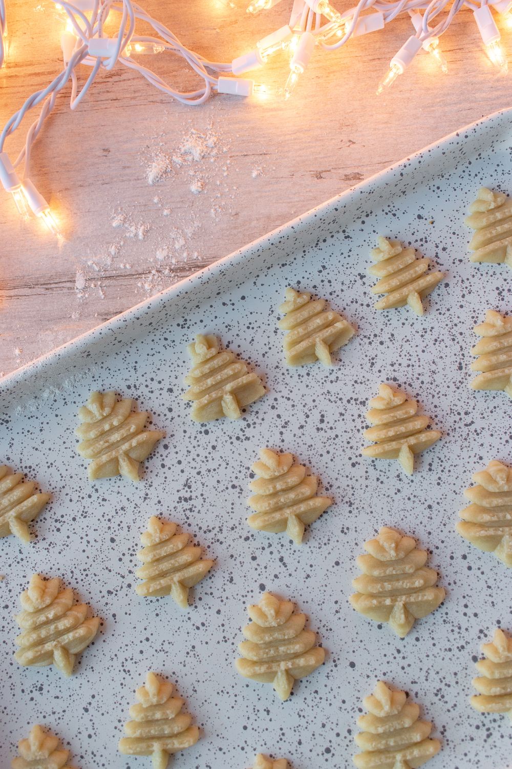 Raw dough Christmas spritz cookies pressed shapes on baking sheet