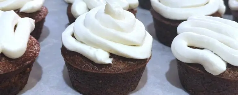 Rows of spiced carrot cupcakes topped with cream cheese frosting.