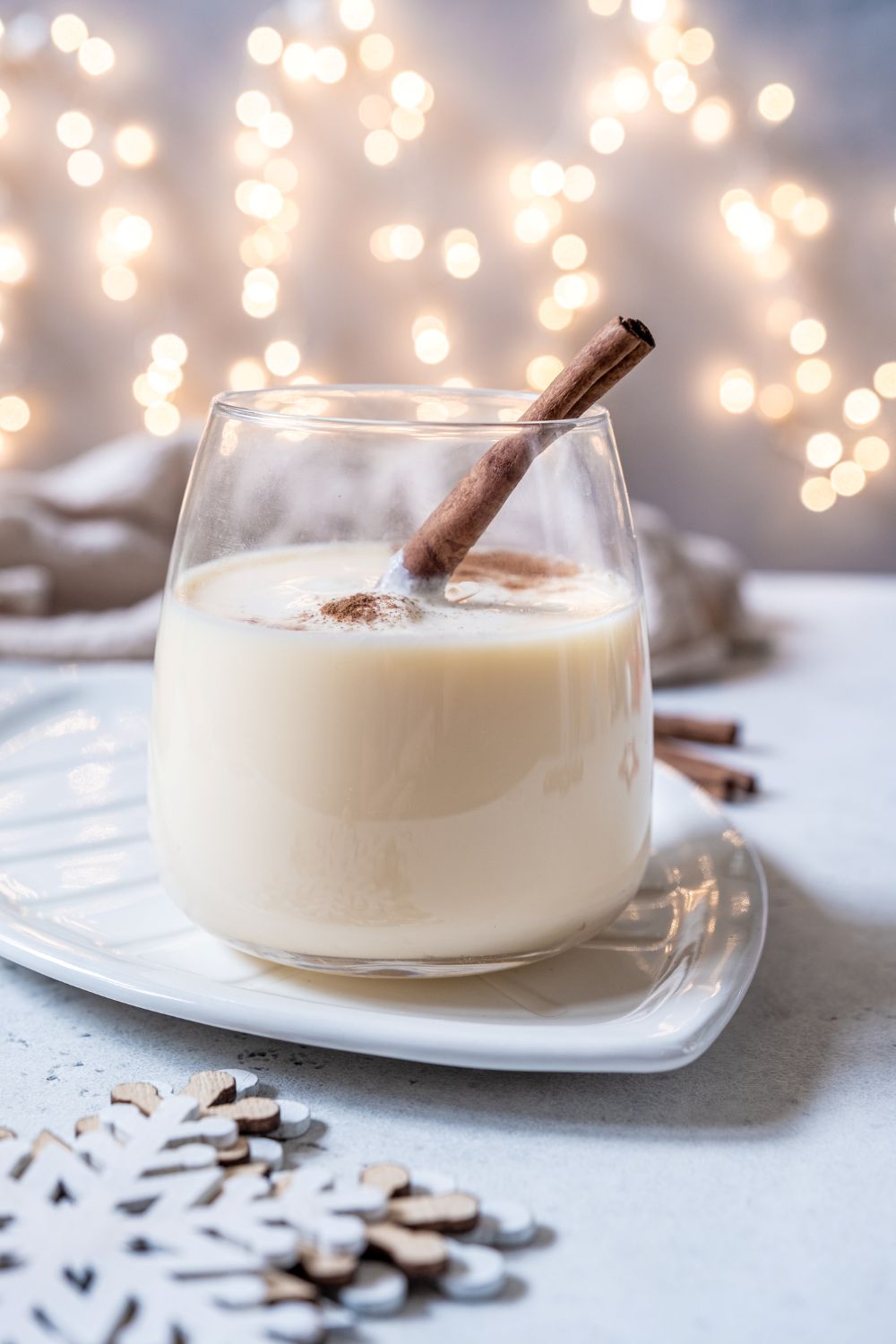 Creamy eggnog in a clear glass with a cinnamon stick