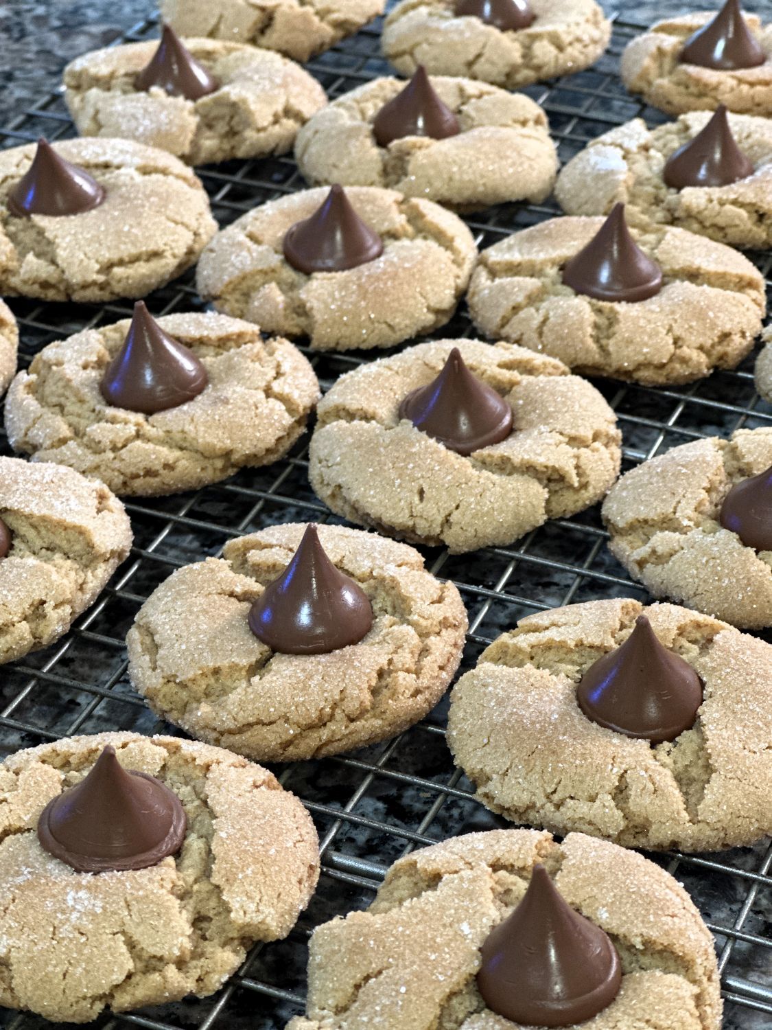 A fresh-baked batch of Classic Peanut Butter Blossoms cooling on a wire rack