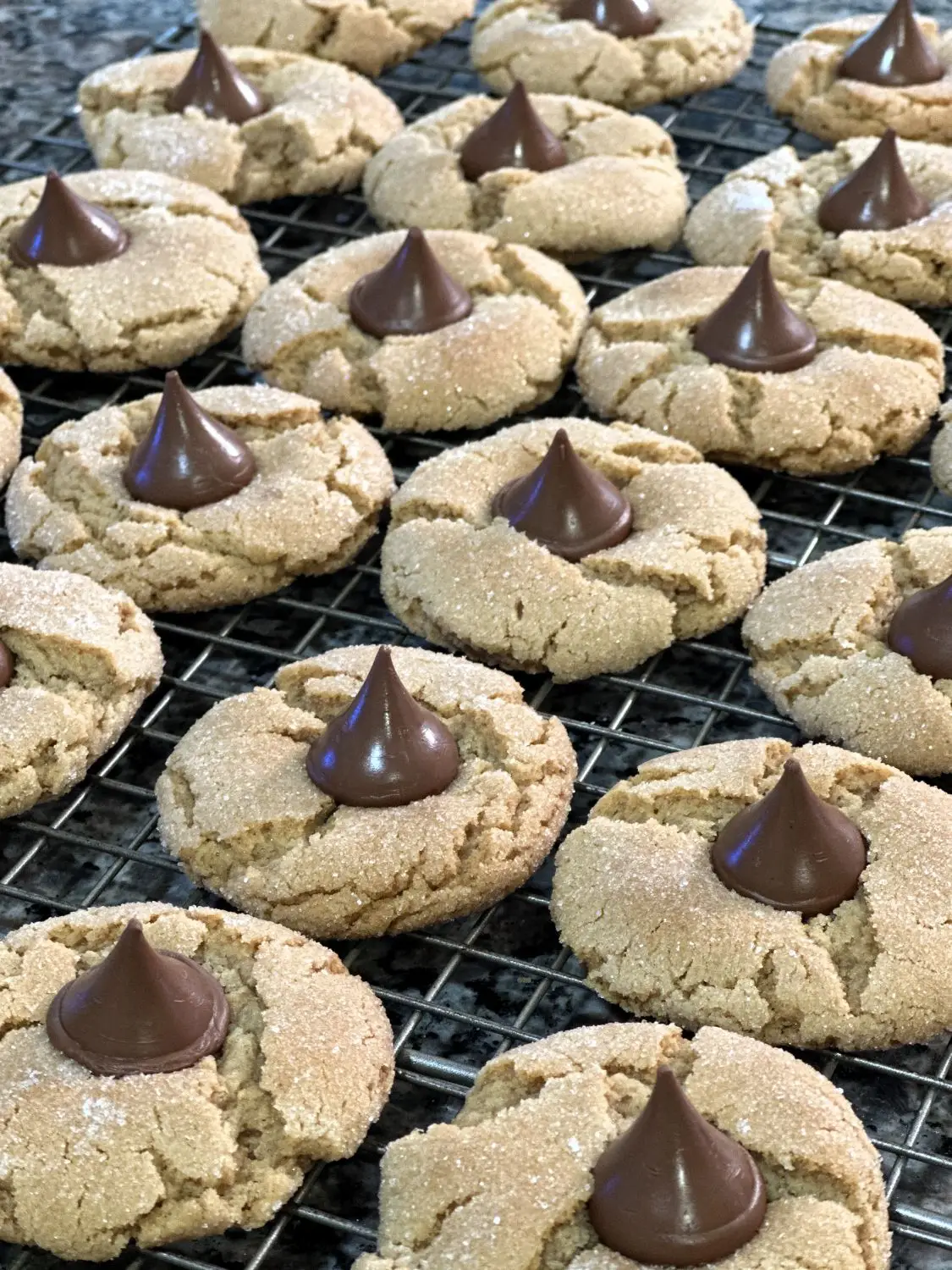 A fresh-baked batch of Classic Peanut Butter Blossoms cooling on a wire rack