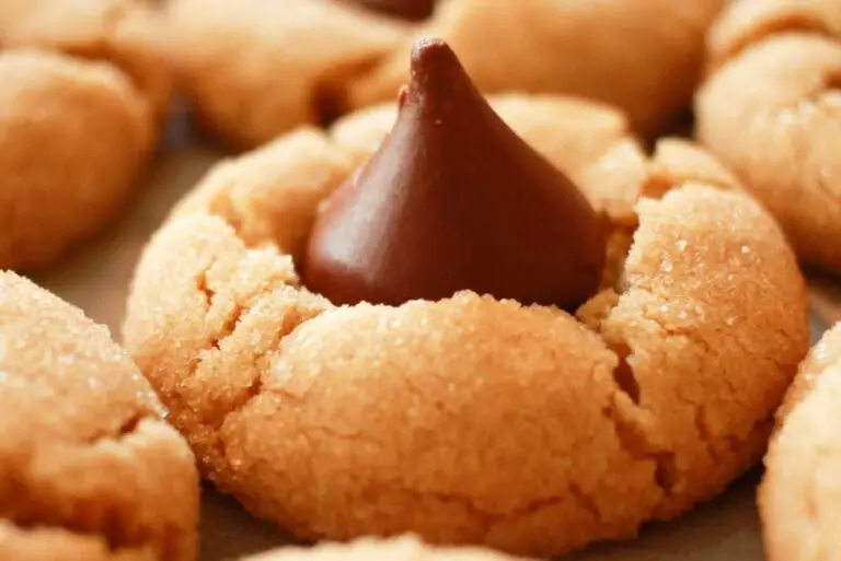 Classic peanut butter blossoms cookies with chocolate kisses on cooling rack, showing crackled sugar coating and soft texture