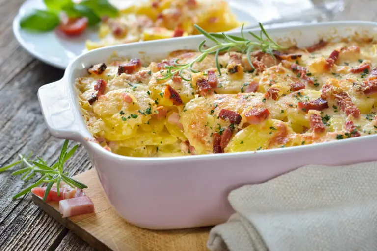 Hearty ham and potato casserole with cream of cheddar cheese soup in white casserole dish