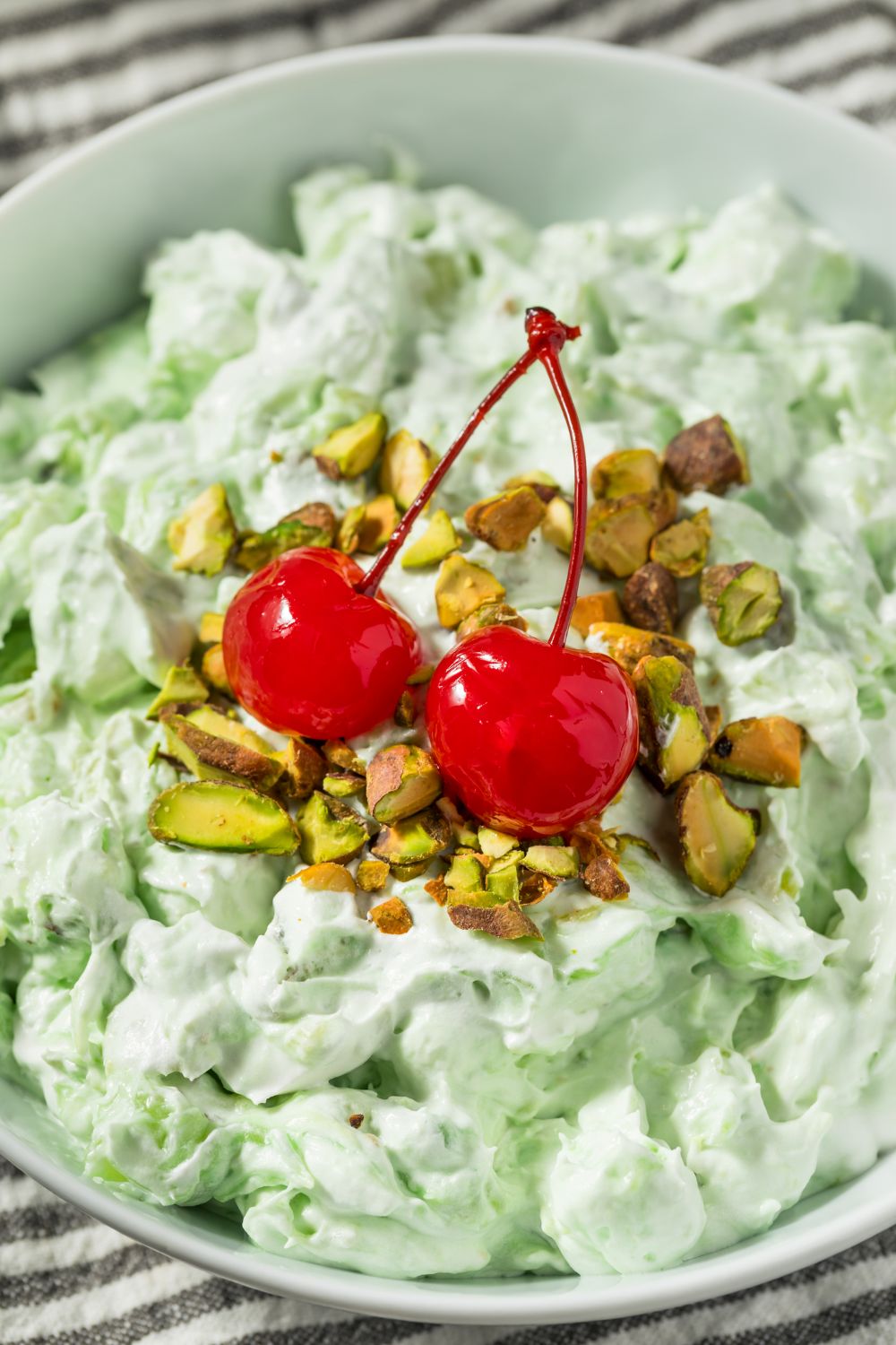 Green Watergate salad topped with chopped nuts and maraschino cherries 