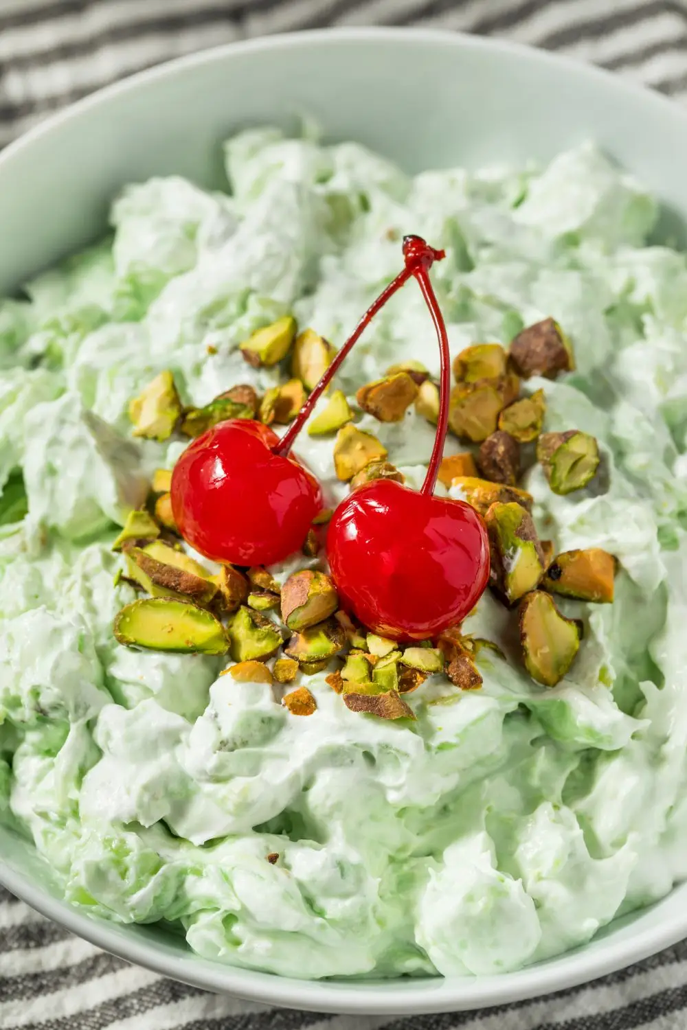 Green Watergate salad topped with chopped nuts and maraschino cherries