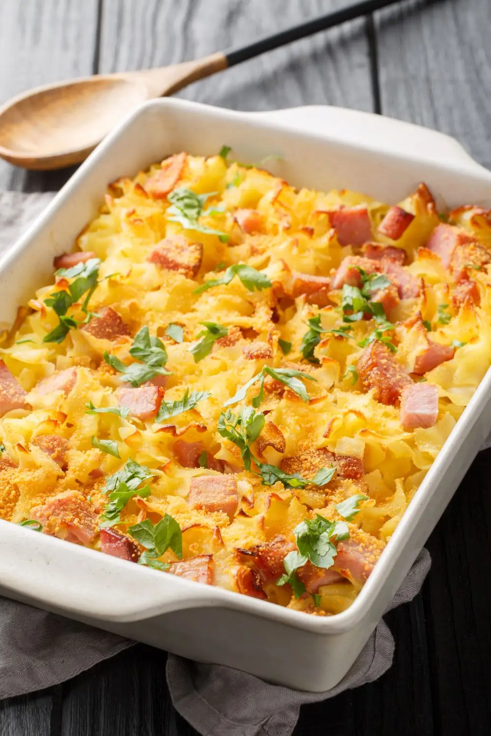 Hearty ham and potato casserole with cream of cheddar cheese soup in white casserole dish