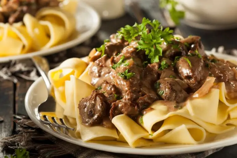 Classic beef stroganoff with tender sirloin strips and mushrooms in creamy sauce served over egg noodles on a white plate