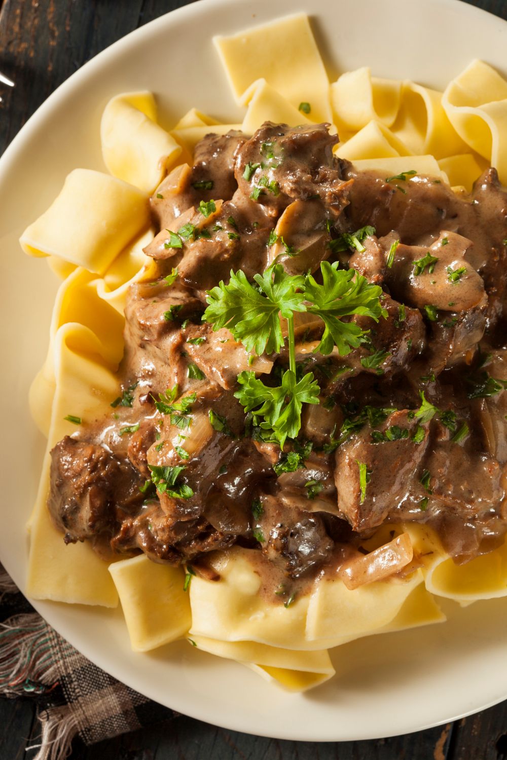 Classic beef stroganoff with tender sirloin strips and mushrooms in creamy sauce served over egg noodles on a white plate
