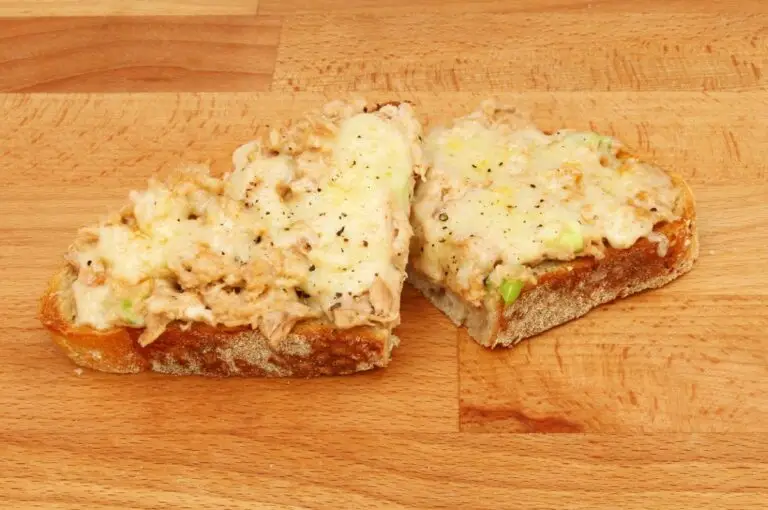 Vintage tuna rarebit open-faced sandwich on a butcher block board.