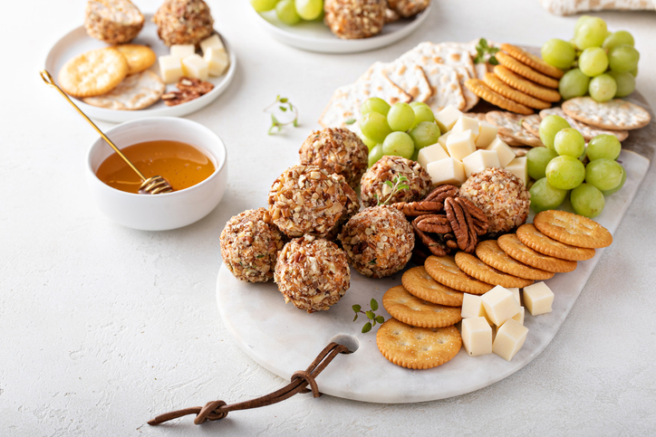 Cheese balls or truffles on a cheese board with crackers and grapes