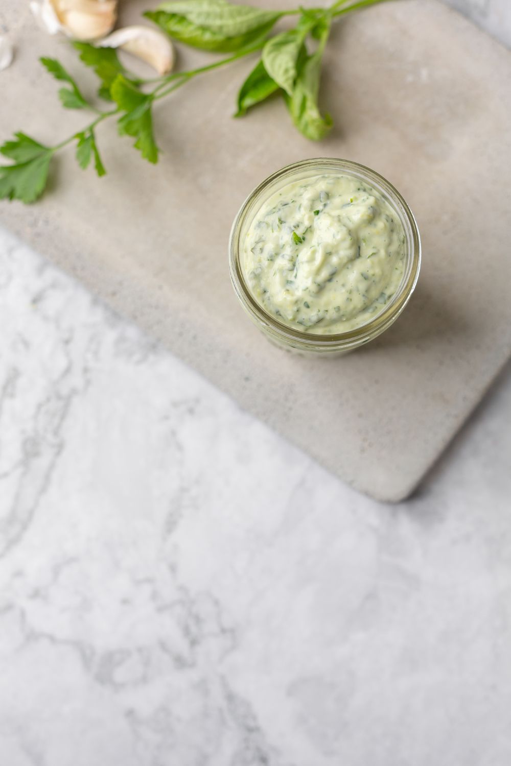 Jar of homemade green goddess dressing on a concrete cutting board
