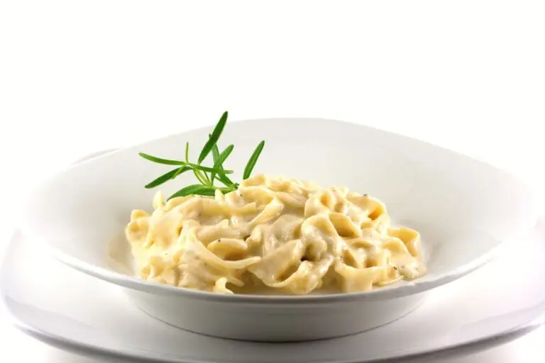 White pasta bowl filled with fettuccine and homemade alfredo sauce with parmesan