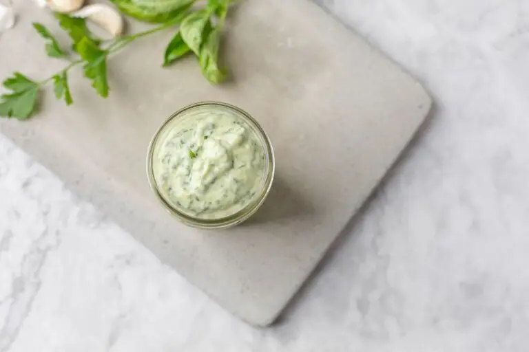 Jar of homemade green goddess dressing on a concrete cutting board