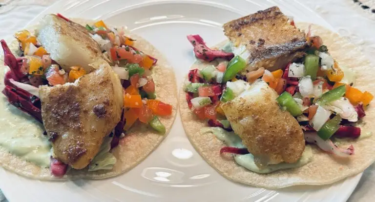 two baja fish tacos with pan seared cod, cabbage slaw, pico de gallo, and creamy avocado sauce