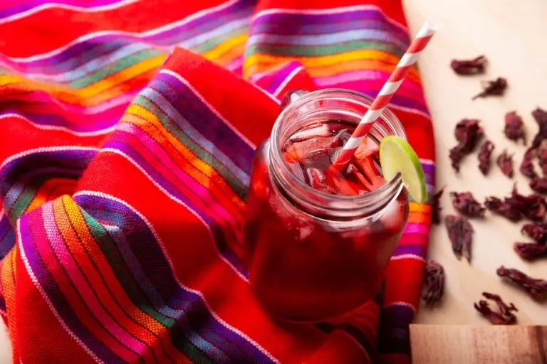 easy agua fresca recipes - agua de jamaica shown here in a mason jar with red & white paper straw