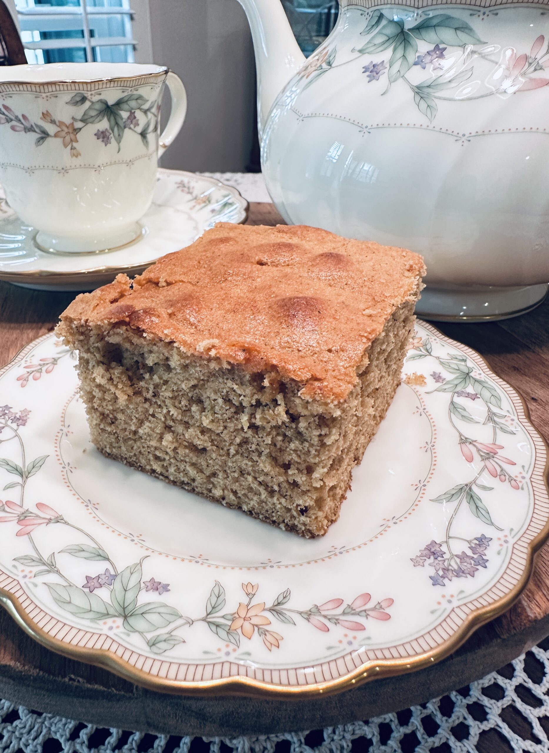 Vintage 1944 wartime spice cake with bacon drippings sliced into a square on a wooden cake stand