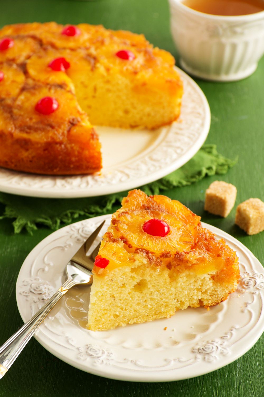 Classic pineapple upside down cake recipe on a white serving platter with golden caramelized pineapple rings, bright red maraschino cherries, and a tender vanilla cake crumb