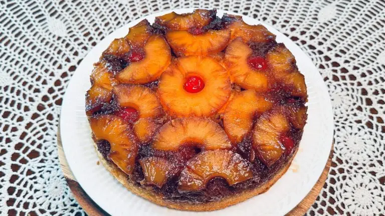 Classic pineapple upside-down cake recipe on a white serving platter with golden caramelized pineapple rings, bright red maraschino cherries, and a tender vanilla cake crumb