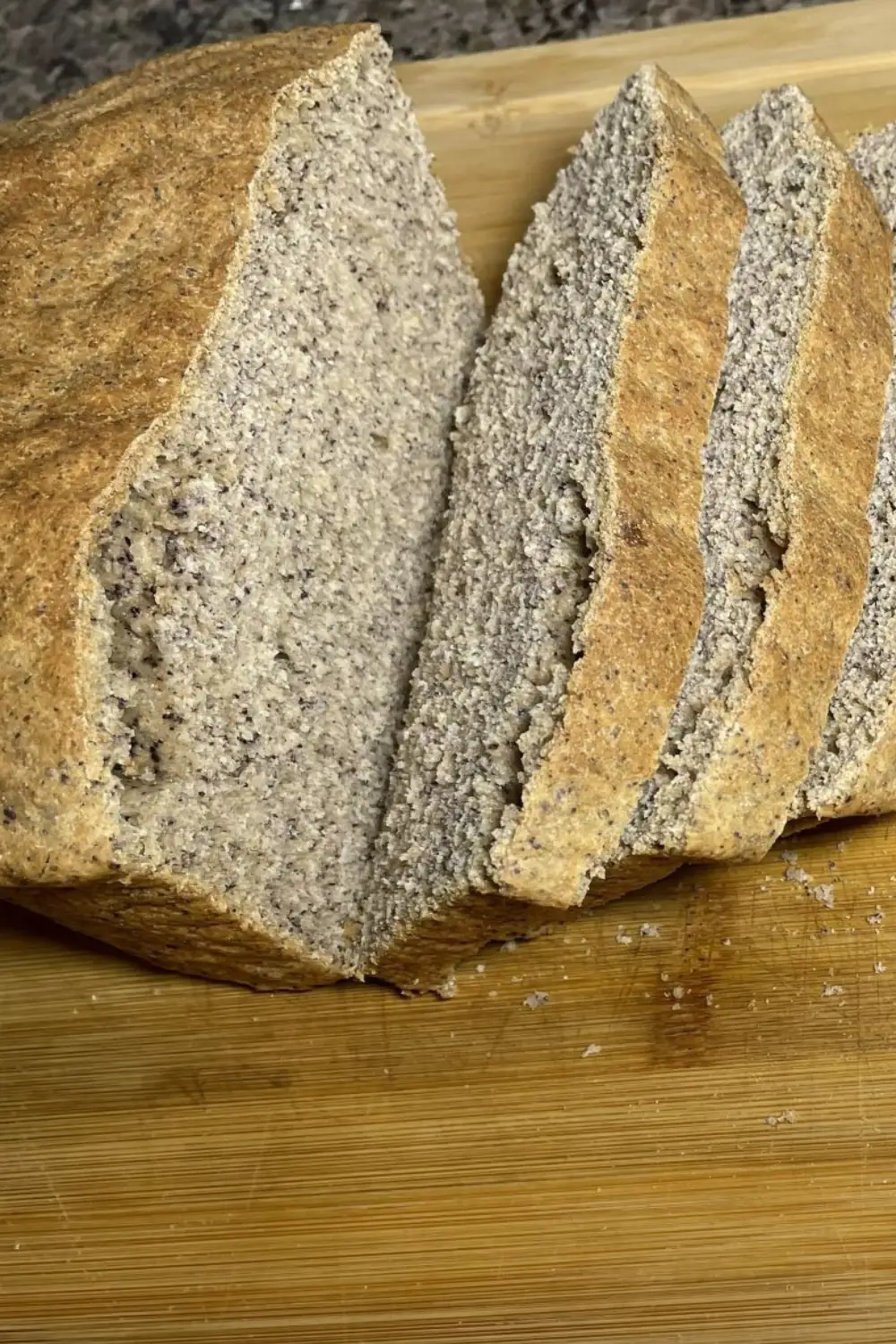 sliced black bean flour bread on a wooden cutting board.