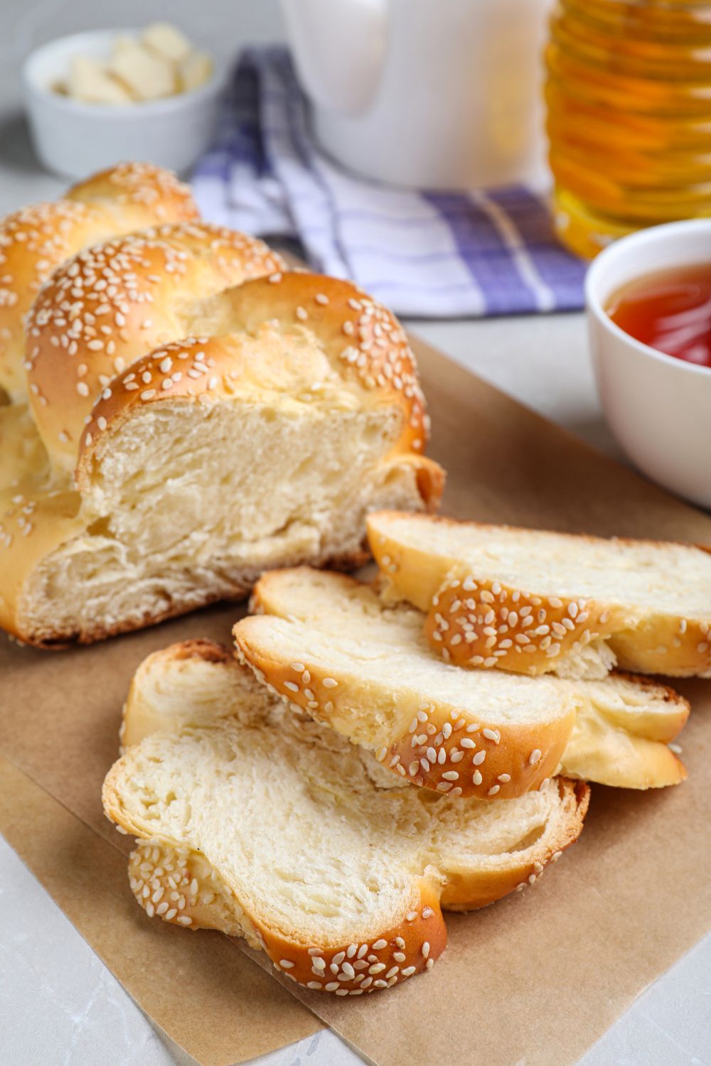 sliced homemade braided challah bread topped with sesame seeds