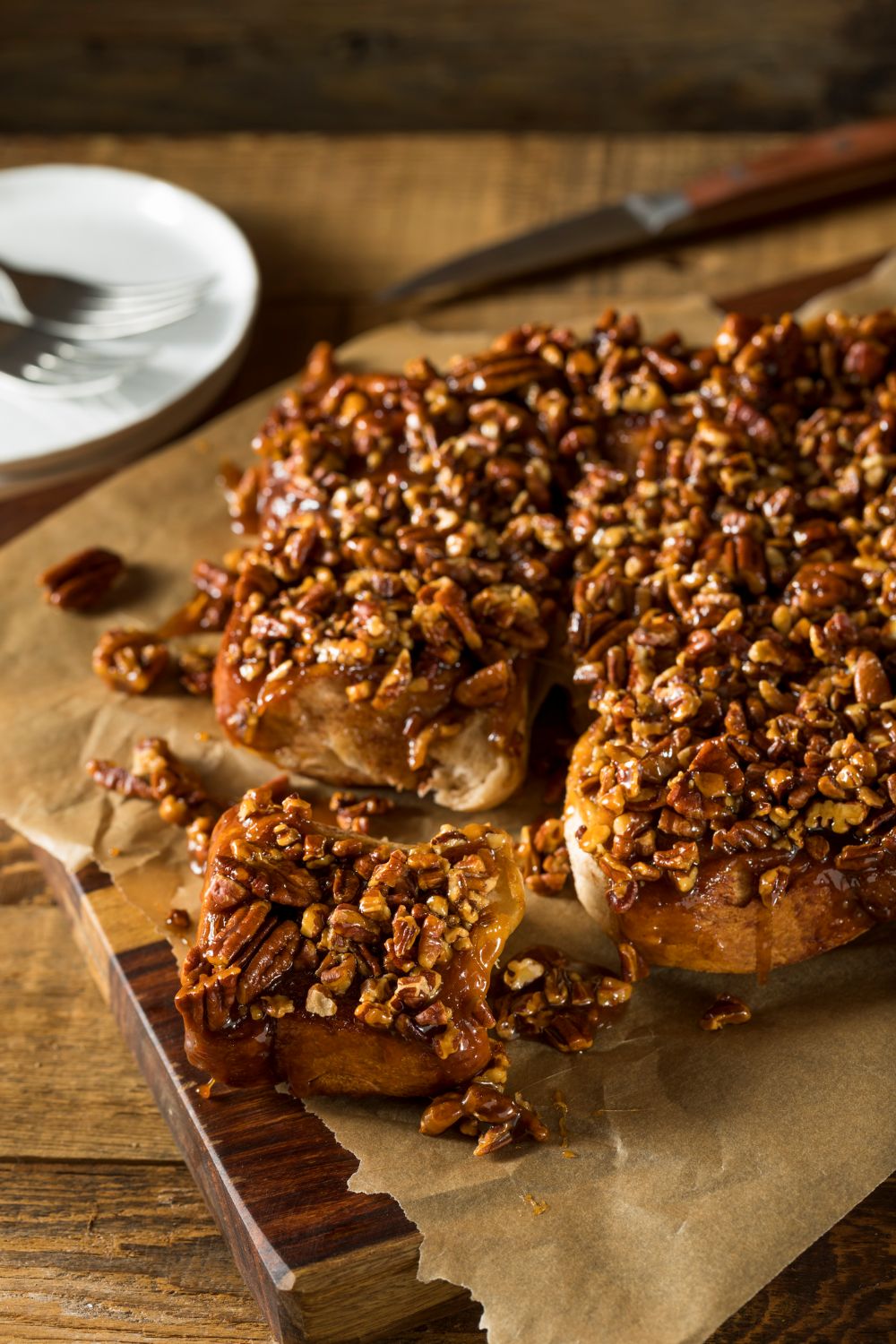 Homemade pecan sticky buns on parchment paper with gooey caramel sauce and whole pecans, baked golden brown from scratch
