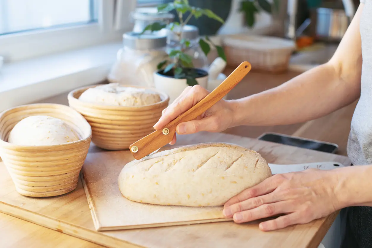 scoring bread dough with a bread lame at a 45 degree angle