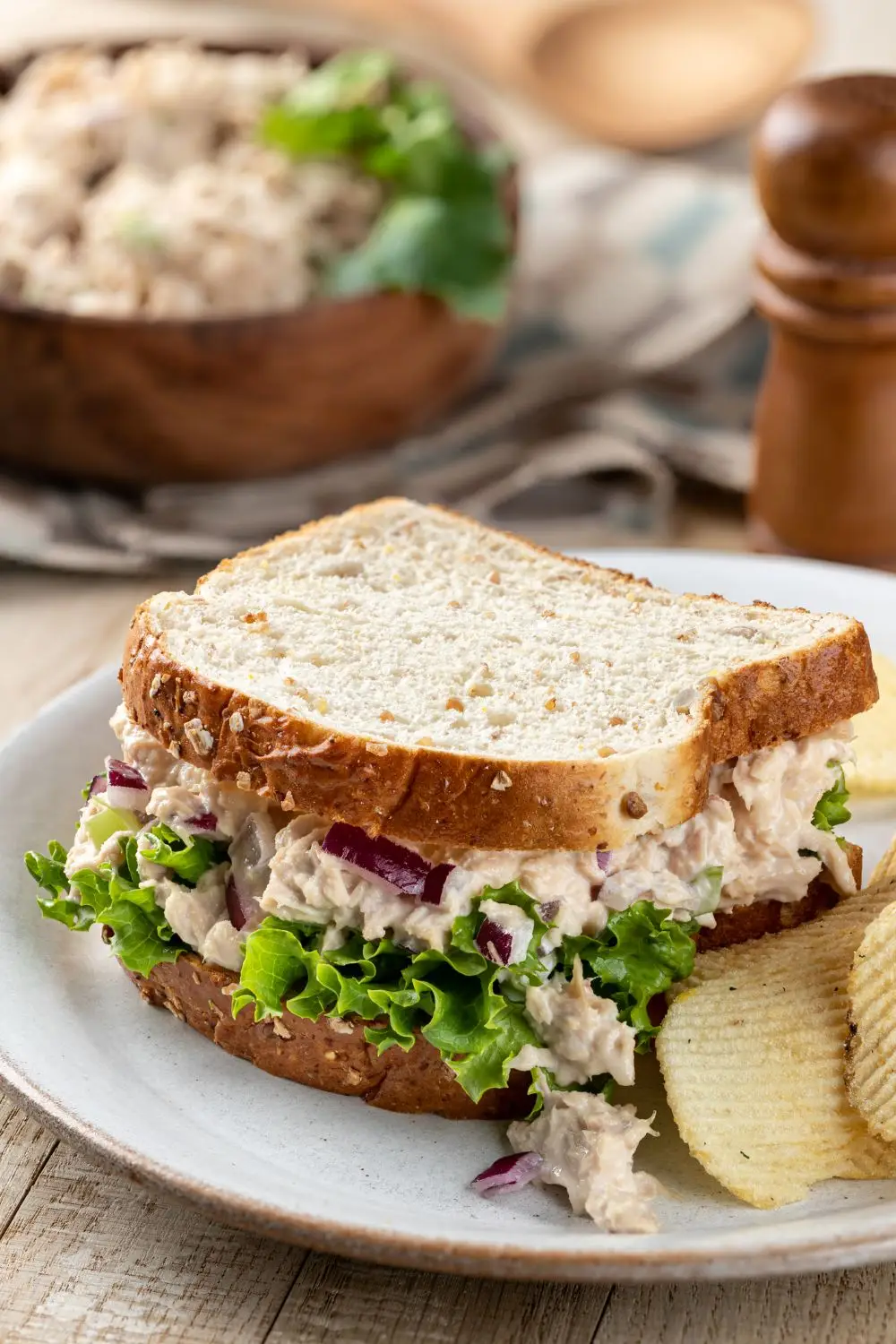 Close up of this easy tuna salad sandwich on whole grain bread with potato chips on the side