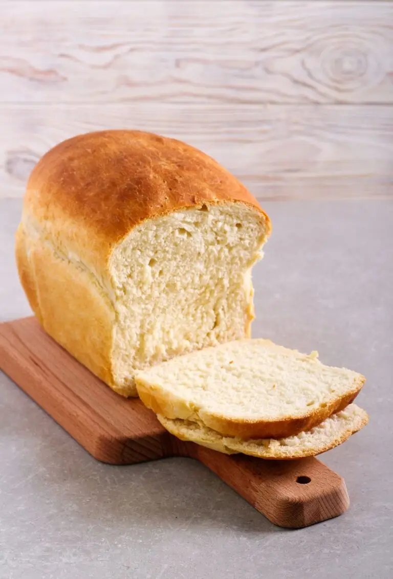 The Amish white bread recipe shown here baked tall and soft; sliced loaf appears on a wooden cutting board.